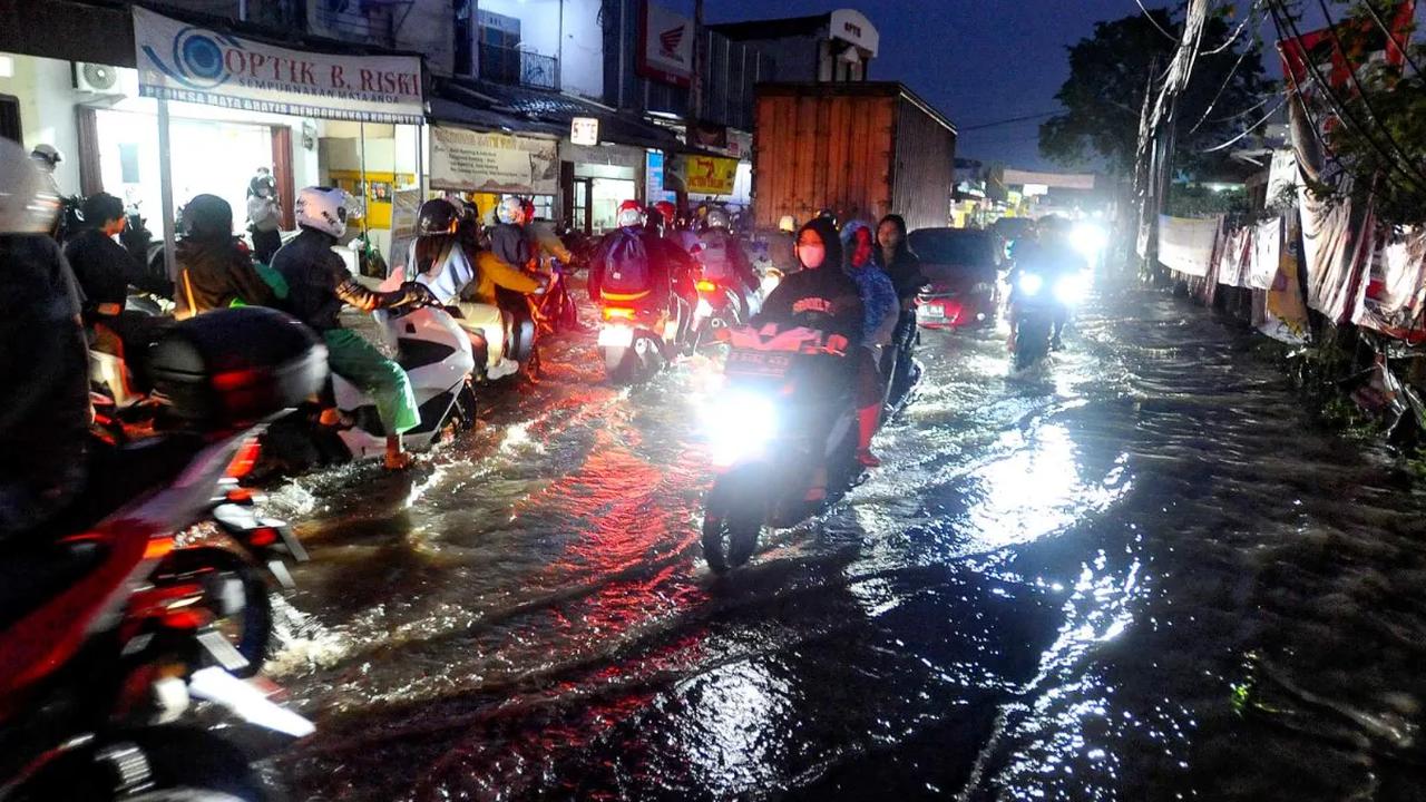 Para pengendara bermotor terpaksa memperlambat laju kendaraannya saat melewati genangan banjir yang merendam kawasan Jalan Dr. Setiabudi, Pamulang, Tangerang Selatan, Rabu (06/12/2023).