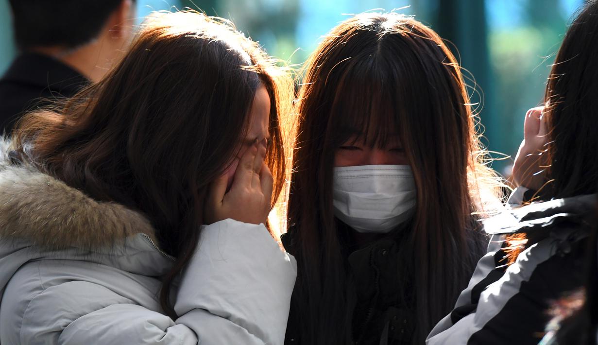 Tangis sejumlah fans saat memberikan penghormatan kepada Jonghyun SHINee di rumah duka Seoul Asan Hospital, Selasa (19/12). Pihak keluarga tidak akan melakukan autopsi dan menerima kematian Jonghyun sebagai akibat dari aksi bunuh diri (JUNG Yeon-Je / AFP)