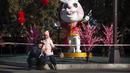 Seorang pria dan wanita berpose untuk selfie di depan patung kelinci untuk Tahun Baru Imlek mendatang di sebuah taman umum di Beijing, Jumat, 20 Januari 2023. Berbagai hiasan dan pernak-pernik mulai menghiasi Taman di Beijing menjelang perayaan Tahun Baru Imlek. (AP Photo/Mark Schiefelbein)
