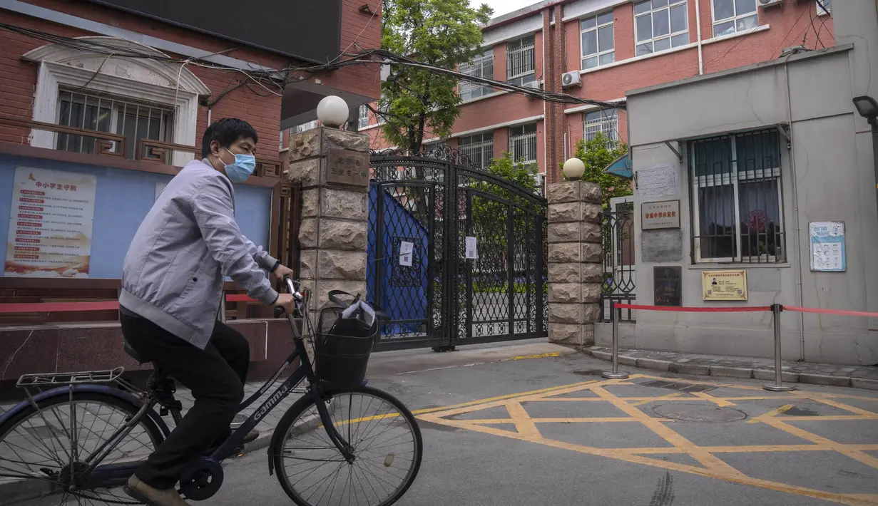 <p>Seorang pria yang mengenakan masker berkendara melewati sekolah menengah yang ditutup di distrik Chaoyang, Beijing, Kamis (28/4/2022). Beijing mengalihkan lebih banyak kelas secara online pada hari Kamis dalam pengetatan pembatasan COVID-19 lebih lanjut, karena ibu kota China berupaya mencegah penyebaran yang lebih luas. (AP Photo/Mark Schiefelbein)</p>