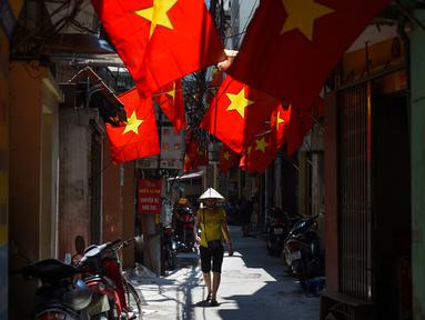 Warga berjalan di sepanjang gang yang dihiasi bendera nasional Vietnam menjelang perayaan Hari Nasional Vietnam di Hanoi (1/9/2020). Peringatan 75 tahun Hari Nasional Vietnam jatuh pada tanggal 2 September 2020. (AFP Photo/Nhac Nguyen)