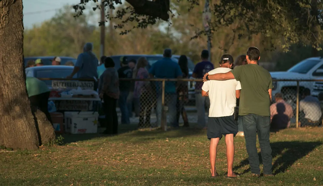 Orang-orang berdiri di dekat lokasi penembakan massal di Gereja First Baptist, Texas, (5/11). Pemuda 26 tahun pelaku penembakan mulai menembak dari luar gereja sesaat setelah keluar dari kendaraannya. (Jay Janner/Austin American-Statesman via AP)