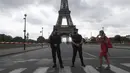 Seorang wanita berjalan melewati petugas polisi yang mengamankan jembatan menuju Menara Eiffel di Paris, Rabu (23/9/2020). Polisi Paris telah memblokir daerah sekitar Menara Eiffel setelah ancaman bom telepon. (AP Photo / Michel Euler)
