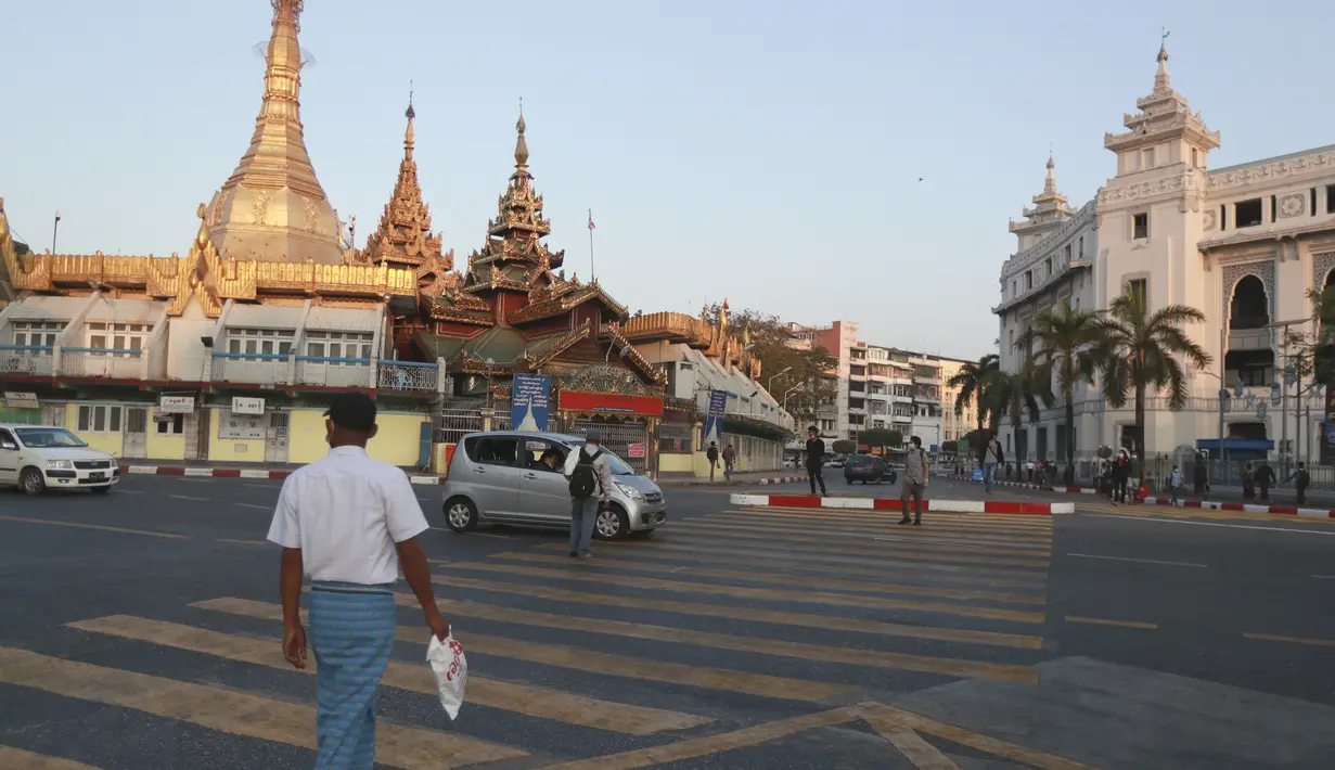 Orang-orang menyeberang jalan dekat Pagoda Sule di Yangon, Myanmar pada Senin (1/2/2021). Militer Myanmar resmi merebut kekuasaan pemerintah usai menahan Kanselir Aung San Suu Kyi dan Presiden Myint pada Senin pagi (1/2). (AP Photo/Thein Zaw)