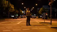 Seorang polisi berjaga di sebuah jalan di dekat pusat perbelanjaan Olympia Einkaufzentrum (OEZ) di Munich, Jerman (22/7). Penembakan ini hanya berselang tiga hari setelah terjadinya penyerangan di kereta api Jerman. (AFP PHOTO/Christof Stache)