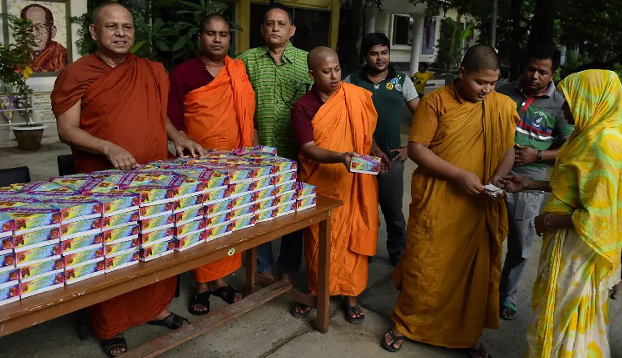 Sejumlah biksu saat membagikan iftar (makanan berbuka puasa) kepada umat muslim di Wihara Dhammarajika, Dhaka, Bangladesh, Selasa (7/7). Ini merupakan momen langka keharmonisan umat beragama di negara Asia. (AFP PHOTO/Munir uz ZAMAN)