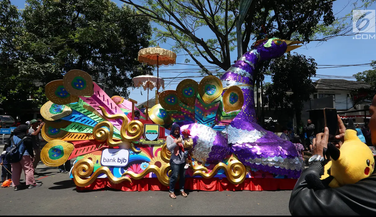 Seorang warga berfoto di kendaraan karnaval sebelum dimulainya Karnaval Kemerdekaan Pesona Parahyangan 2017 di sekitar Gedung Sate, Bandung, Sabtu (26/8). Karnaval ini merupakan rangkaian dan penutupan HUT Kemerdekaan RI ke-72. (Liputan6.com/Johan Tallo)