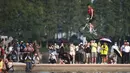 Orang-orang menonton seorang pesepeda yang melompat ke Danau Timur menggunakan sepeda BMX dalam ajang tahunan festival lompat air (water jump) BMX di Wuhan, ibu kota Provinsi Hubei, China tengah, pada 22 Agustus 2020. (Xinhua/Xiao Yijiu)