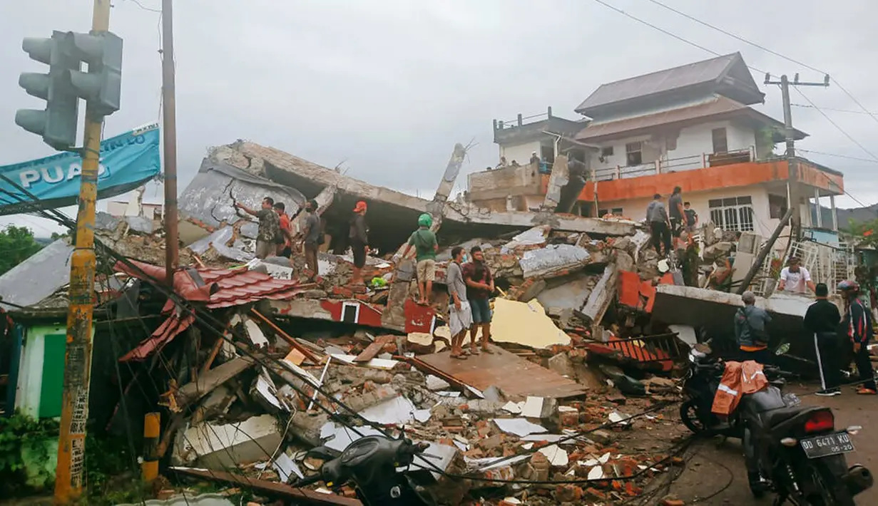 Warga memeriksa bangunan yang rusak akibat gempa di Mamuju, Sulawesi Barat, Indonesia, Jumat (15/1/2021). Sejumlah rumah dan bangunan di Mamuju roboh akibat gempa dengan berkekuatan 6,2 skala Richter yang berpusat di timur laut Majene. (AP Photo/Rudy Akdyaksyah)