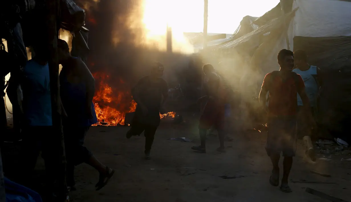Para penambang emas ilegal berlarian saat kampnya dibakar oleh polisi di Mega 14, di Madre de Dios, Amazon selatan, Peru, (13/7/2015). 10 persen hasil tambang emas ilegal ini menguasi pasar nasional Peru. (REUTERS/Janine Costa)