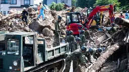Tim penyelamat dan tentara membersihkan puing-puing yang berserakan usai banjir melanda Kumano, Prefektur Hiroshima, Jepang, Senin (9/7). Prefektur Hiroshima menjadi kawasan yang terdampak paling parah. (Martin BUREAU/AFP)