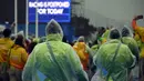 Relawan mengenakan jas hujan sambil mengamati layar billboard yang mengumumkan pembatalan kompetisi cabang dayung Olimpiade 2016 akibat cuaca buruk di stadion Lagoa, Rio de Janeiro, 10 Agustus 2016. (AFP PHOTO/Damien Meyer)