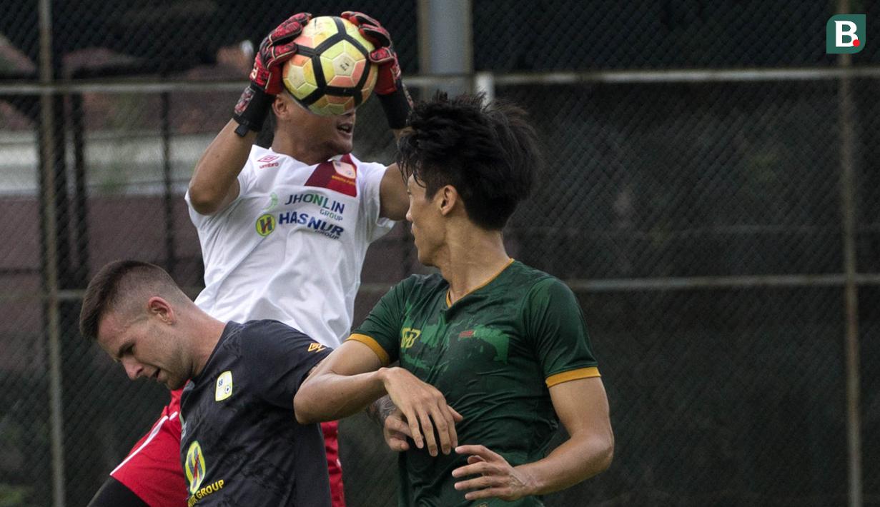 Kiper Barito Putera, Dian Agus, mengamankan bola dari bek PS Tira, Kim Sang Min, pada laga persahabatan di Lapangan Bais, Bogor, Kamis (22/2/2018). PS Tira kalah 1-2 dari Barito Putera. (Bola.com/Asprilla Dwi Adha)