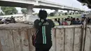 Polisi berbincang dengan warga di dekat pagar pembatas menuju kawasan Cipinang Melayu, Jakarta, Minggu (29/3/2020). Warga membatasi aktivitas pengunjung yang melintasi kawasan mereka dengan menutup sebagian jalan dengan seng guna mengantisipasi penyebaran corona Covid-19. (merdeka.com/Iqbal Nugroho)