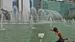 Seorang anak melompat ke kolam di Bundaran HI, Jakarta, Senin (17/6/2019). Meski ada larangan berenang, sejumlah anak tetap nekat menyebur ke kolam Bundaran HI. (Liputan6.com/Herman Zakharia)