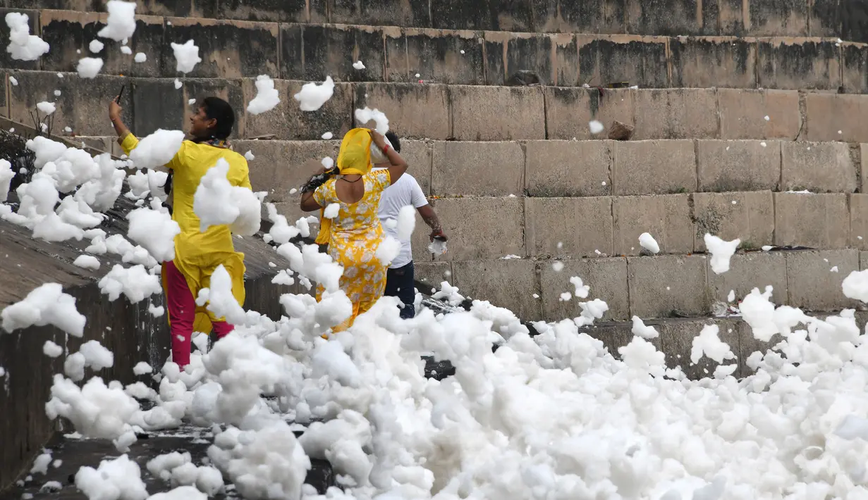 Orang-orang mengambil gambar dekat busa yang memenuhi sungai Yamuna di New Delhi, 23 September 2018. Sungai yang juga dianggap suci oleh umat Hindu India ini kini tercemar hebat, salah satunya akibat busa polusi yang memenuhinya. (AFP/Dominique FAGET)