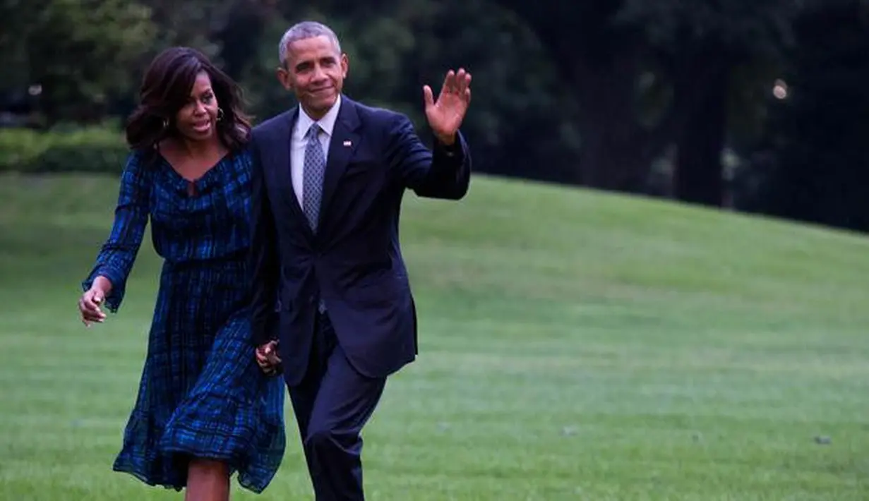 Presiden Amerika Serikat (AS) ke-44, Barack Obama menggandeng tangan sang istri, Michelle Obama, sambil menyapa awak media saat berjalan di halaman sisi selatan Gedung Putih di Washington, 28 September 2016. (AFP PHOTO / ZACH GIBSON)