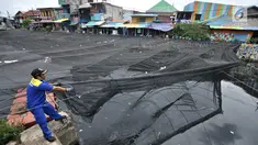 Petugas melepas kain waring atau jaring yang menutupi Kali Item di Kemayoran Jakarta, Rabu (14/11). Pelepasan waring yang sebagian dalam kondisi sudah robek itu dilakukan lantaran banyak warga yang membuang sampah di atasnya (Merdeka.com/Iqbal S. Nugroho)
