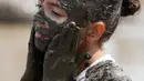 Tmiamelia Harris, 11, mengaplikasikan lumpur ke wajahnya saat Mud Day atau Hari Lumpur di Michigan, negara bagian AS, Selasa (9/7/2019). Para peserta perayaan yang menjadi tradisi setiap tahun ini merupakan anak-anak untuk agar mereka bersenang-senang selama liburan musim panas.  (AP/Carlos Osorio)