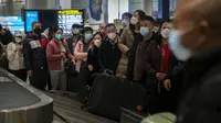 Pelancong yang memakai masker menunggu barang bawaan mereka di area kedatangan internasional di Bandara Internasional Ibukota Beijing di Beijing, Senin (9/1/2023). Pelancong internasional pertama tiba di China tanpa karantina wajib yang telah diberlakukan pada awal penerbangan. Pandemi tiga tahun lalu setelah pembatasan dicabut mulai hari Minggu. (AP/Mark Schiefelbein)