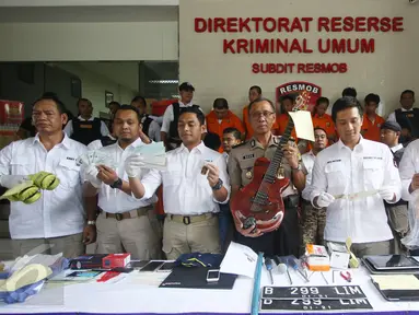 Petugas menujukan barang bukti beserta tersangka berbagai kasus yang berhasil diungkap dalam rilis di Polda Metro Jaya, Jakarta, Jumat (17/2). (Liputan6.com/Immanuel Antonius)