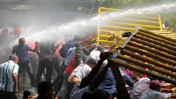 Polisi menembakkan air ke arah pendemo yang mulai rusuh saat aksi protes di dekat sekretariat presiden di Kolombo, Sri Lanka, Rabu (1/2). Pendemo menentang rencana privatisasi pelabuhan oleh pemerintah. (AP Photo / Eranga Jayawardena)