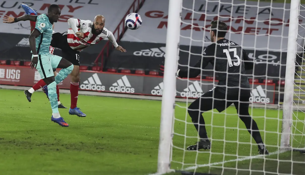 Pemain Sheffield United, David McGoldrick menyundul bola ke arah kiper Liverpool, Adrian pada pertandingan lanjutan Liga Inggris di stadion Bramall Lane di Sheffield, Inggris, Senin (1/3/2021). Kini Liverpool berada di posisi keenam klasemen Liga Inggris. (Lee Smith, Pool via AP)