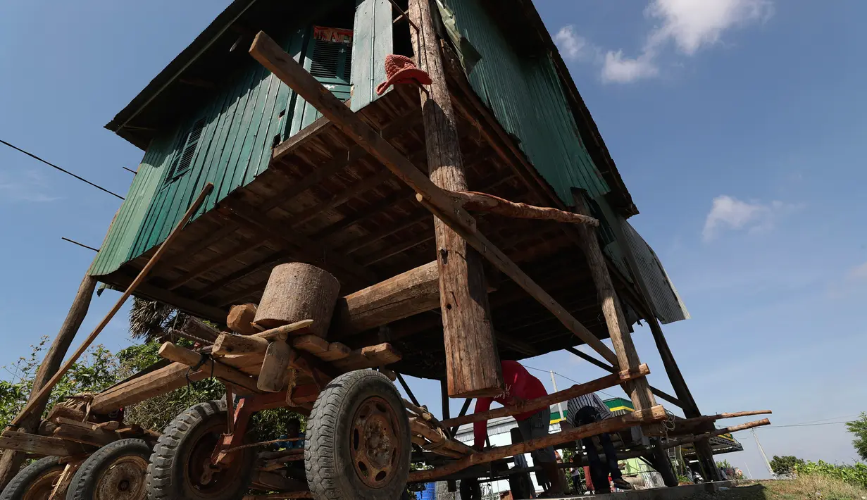 Penduduk desa Kamboja memindahkan sebuah rumah kayu di desa Pon Sang di sisi utara Phnom Penh, Kamboja (26/4/2020). Ini adalah cara bergerak tradisional yang dikumpulkan penduduk desa untuk saling membantu dengan menggunakan traktor dan batang kayu. dengan menjaga rumah tetap utuh. (AP/Heng Sinith)