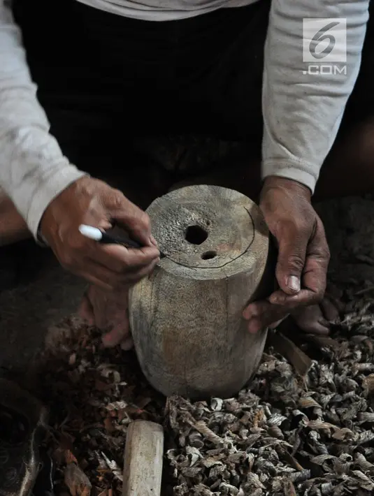 Perajin Oman Sumarna menyelesaikan pembuatan patung di Sanggar Primitif, Sawangan, Depok, Rabu (9/1). Sanggar kerajinan pahatan kayu tradisional itu mengambil tema-tema primitif untuk melestarikan budaya Indonesia. (Liputan6.com/Herman Zakharia)