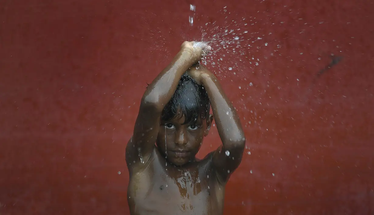 Seorang anak mandi dengan air hujan di La Guaira, Venezuela pada 26 Juli 2020, di tengah pandemi virus corona COVID-19  ketika sisa-sisa Badai Tropis Gonzalo melewati Karibia. (AP Photo / Matias Delacroix)