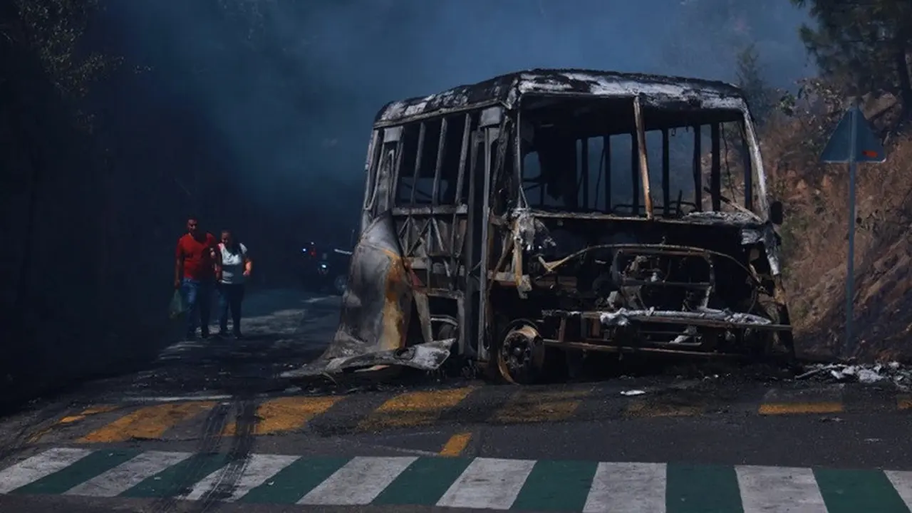 Warga berjalan melewati kendaraan yang hangus terbakar di sebuah jalan di Cointzio, Negara Bagian Michoacan, Meksiko, Minggu, (22/2/2026). Kendaraan tersebut dibakar menyusul tewasnya pemimpin Kartel Narkoba CJNG El Mencho.kha