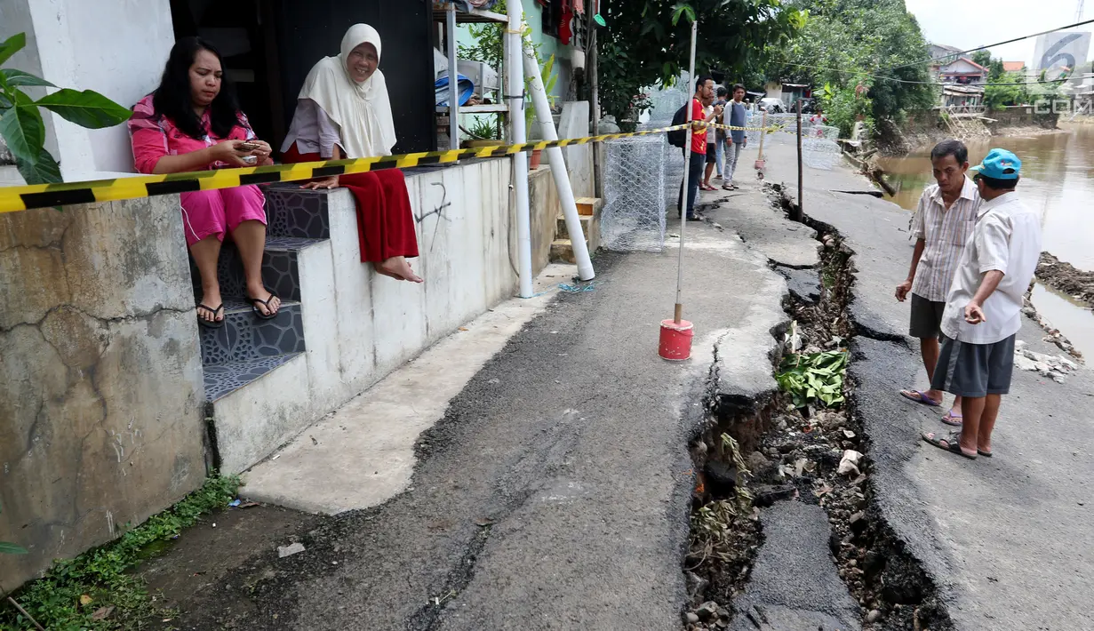 Sejumlah warga mengamati jalan retak di Kelurahan Kebon Manggis, Kecamatan Matraman, Jakarta Timur, Jumat (16/2). Tak hanya retak, jalan yang tepat berada di pinggir anak sungai Ciliwung itu juga sempat mengalami longsor. (Liputan6.com/Johan Tallo)