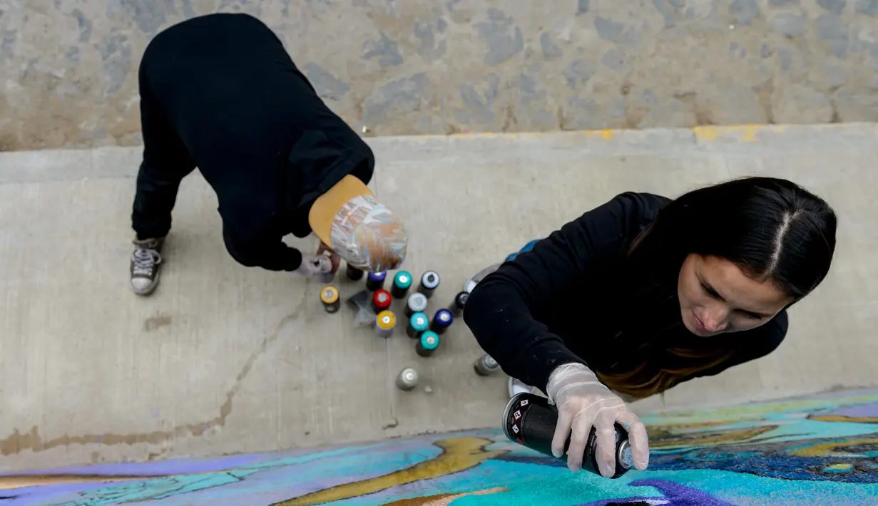 Seniman Sammy Espinosa (kanan) dan istrinya Cynthia Aguilera menyelesaikan pembuatan mural jalanan di Valparaiso, Chile, 9 April 2019. Mural buatan Sammy Espinosa dan Cynthia Aguilera menjadi salah satu objek wisata terpopuler di Valparaiso. (Martin BERNETTI/AFP)