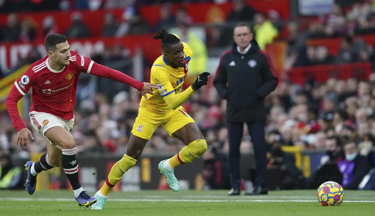 Pemain Manchester United Diogo Dalot (kiri) berebut bola dengan pemain Crystal Palace Wilfried Zaha pada pertandingan Liga Inggris di Stadion Old Trafford, Manchester, Inggris, 5 Desember 2021. Manchester United menang 1-0. (AP Photo/Jon Super)