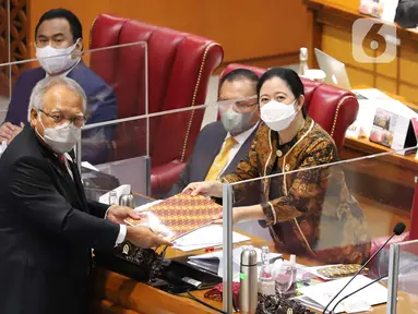 Menteri PUPR Basuki Hadimuljono (kiri) menyerahkan dokumen kepada Ketua DPR Puan Maharani (kanan) pada Rapat Paripurna ke-11 Masa Persidangan II Tahun Sidang 2021-2022 di Kompleks Parlemen, Jakarta, Kamis (16/12/2021). (Liputan6.com/Anga Yuniar)