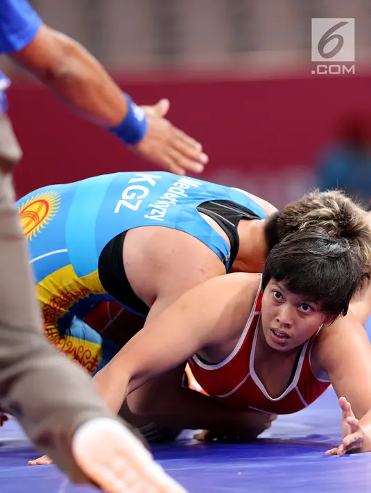 Pegulat Kirgizstan Medet Kyzy Aiperi mengunci pegulat putri Indonesia, Ridwan Ridha Wahyadaniyaty pada kelas putri 76 Kg di JCC Senayan, Selasa (21/8). Pada perdelapan final, Ridha kalah atas lawanya dengan skor 0-12. (Liputan6.com/Fery Pradolo)