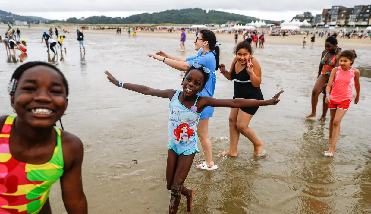 Anak-anak menuju ke laut di pantai Cabourg, barat laut Prancis (18/8/2021). Acara ini sebagai bagian dari kampanye "Lupa Liburan" yang diselenggarakan oleh LSM Prancis Secours Populaire untuk anak-anak yang keluarganya tidak mampu pergi berlibur. (AFP/Sameer Al-Doumy)