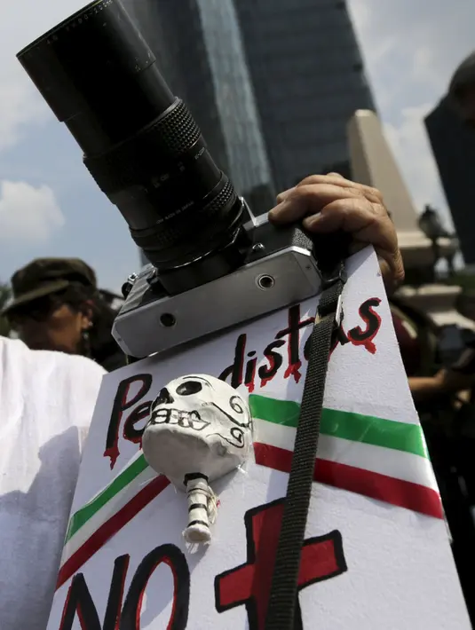 Seseorang  memegang kamera dan patung tengkorak saat menggelar protes di monumen Kemerdekaan, Meksiko, Minggu (2/8/2015). Espinosa ditemukan dengan dua luka tembak bersama empat perempuan lainnya. (REUTERS/Henry Romero)