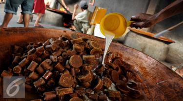 Pekerja menuangkan santan di atas gula aren di kawasan Pasar Minggu, Jakarta, Kamis (23/6). Produksi dodol Betawi mengalami peningkatan tajam seiring permintaan jelang Lebaran. (Liputan6.com/Gempur M Surya)