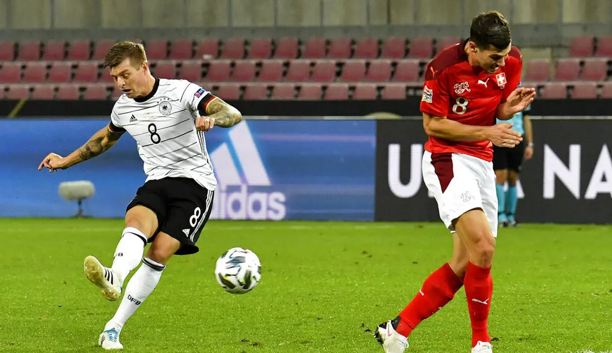 Pemain Jerman Toni Kroos menendang bola melewati pemain Swiss Remo Freuler (kanan) pada pertandingan UEFA Nations League di Cologne, Jerman, Selasa (13/10/2020). Pertandingan berakhir dengan skor 3-3. (AP Photo/Martin Meissner)