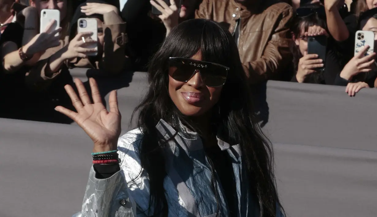 Naomi Campbell menyapa penggemarnya saat tiba menghadiri koleksi busana Louis Vuitton Spring/Summer 2023 yang dipresentasikan selama Paris Fashion Week di Paris pada Selasa, 4 Oktober 2022. Model asal Inggris ini memakai sepasang ankle boots beludru kuning mustard dengan ujung bulat dan tumit blok. (AFP/Geoffroy VAN DER HASSELT)