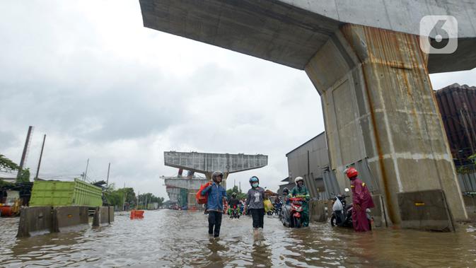 Pengendara mendorong motornya melintasi banjir di Jalan Raya Bekasi, Jakarta Timur, Selasa (25/2/2020). Banjir akibat hujan yang melanda Bekasi sejak Selasa (25/2) dini hari memutus beberapa titik jalan raya di wilayah setempat. (merdeka.com/Imam Buhori)
