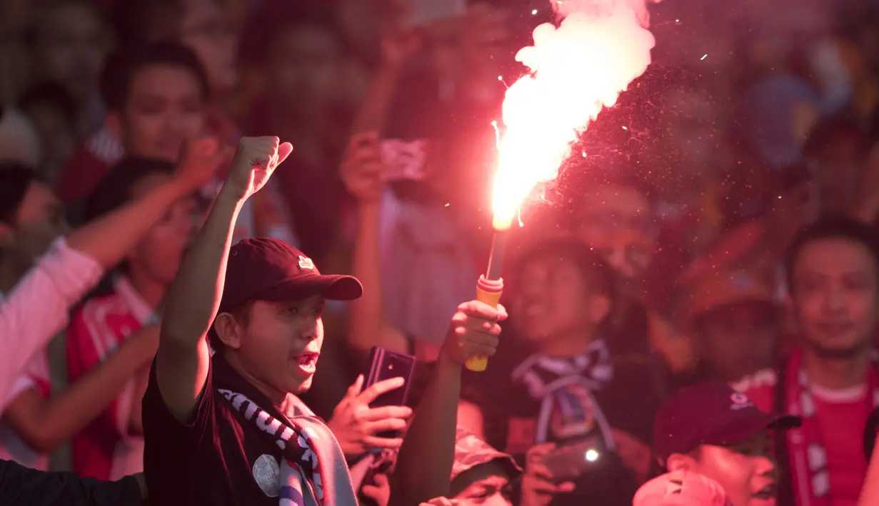 Suporter Persija Jakarta, The Jakmania, menyalakan flare usai mengalahkan Mitra Kukar pada laga Liga 1 di SUGBK, Jakarta, Minggu (9/12). Persija menang 2-1 atas Mitra. (Bola.com/Yoppy Renato)