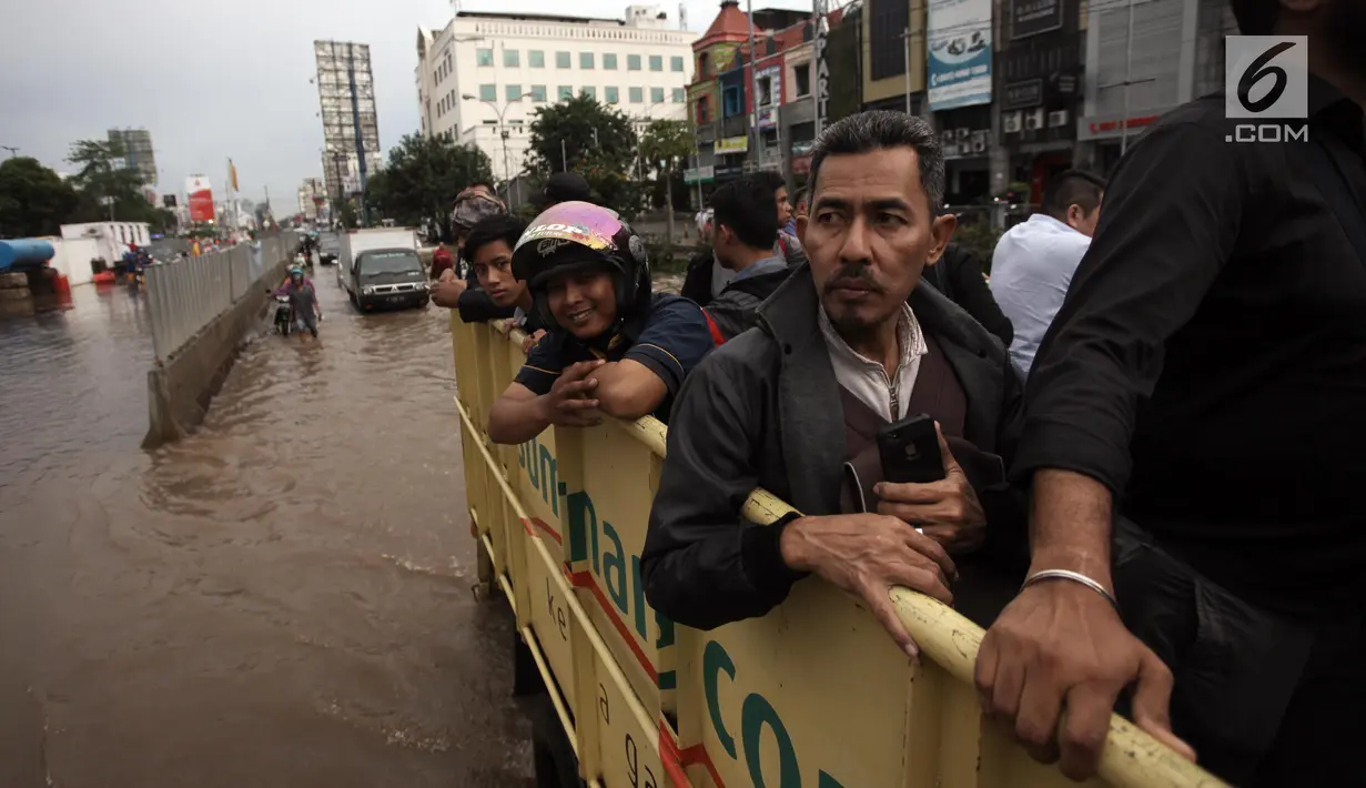 Karyawan dan warga menaiki truk saat dievakuasi dari banjir yang merendam Jalan Boulevard Raya, Kelapa Gading, Jakarta, Kamis (15/2). Banjir diakibatkan guyuran hujan sejak pagi hingga sore. (Liputan6.com/Arya Manggala)