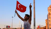 Seorang pria mengibarkan  bendera nasional Turki di Taksim Square, pusat kota Istanbul, Sabtu (16/7). Ratusan warga turun ke jalan merayakan kegagalan kudeta militer di Turki terhadap Pemerintahan Erdogan. (REUTERS/Kemal Aslan)