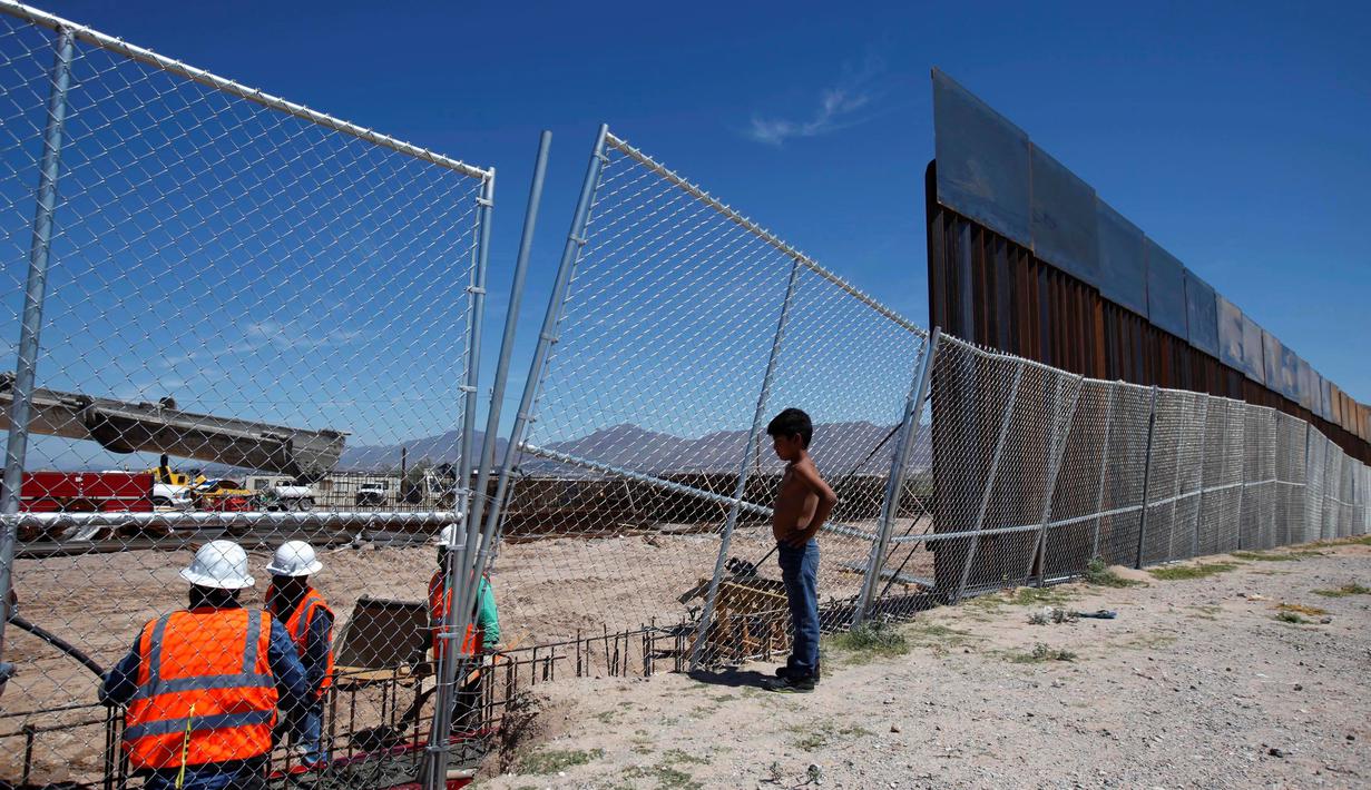 Seorang anak melihat pekerja dari Amerika Serikat saat membangun dinding perbatasan AS-Meksiko di Sunland Park, AS (09/9). Amerika Serikat dan Mexico merupakan dua negara yang memiliki batas geografis yang berdekatan. (REUTERS/Jose Luis Gonzalez)