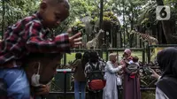 Pengunjung melihat jerapah saat menikmati liburan hari kedua Idul Fitri 1443 H di Taman Margasatwa Ragunan, Jakarta, Selasa (3/5/2022). Dalam pengoperasiannya, pengunjung harus memahami sejumlah syarat dan ketentuan yang dikeluarkan oleh Taman Margasatwa Ragunan, salah satunya soal pembelian tiket. (Liputan6.com/Johan Tallo)