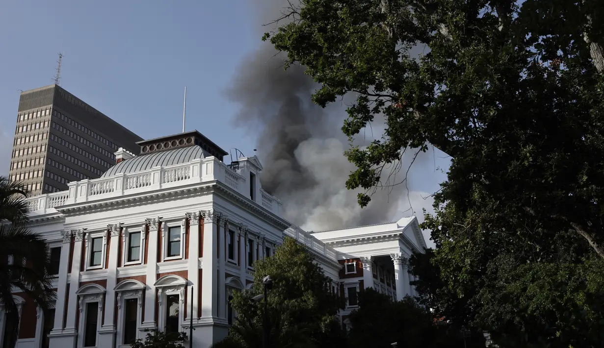 Asap mengepul dari atap sebuah gedung selama insiden kebakaran di kawasan Parlemen Afrika Selatan di Cape Town (2/2/2022). Gedung Parlemen Afrika Selatan dibakar hingga sejumlah bagiannya hancur. Presiden Cyril Ramaphosa berkata hal ini menyakiti rasa demokrasi di Afrika Selatan. (AFP/Marco Longari)