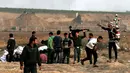 Pemuda Palestina, Mohammad Safy menyapa pengunjuk rasa usai membagikan jus kepada mereka di perbatasan Israel dengan Gaza, Jumat (13/4). (MAHMUD HAMS/AFP)