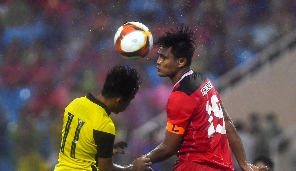 Bek Timnas Indonesia U-23, Fachruddin Wahyudi Aryanto berebut bola udara dengan penyerang Malaysia, Muhammad Syafik bin Ismail dalam pertandingan perebutan medali perunggu SEA Games 2021 di Stadion My Dinh, Minggu (22/5/2022). Indonesia ditahan imbang 1-1 dan menang 4-3 di adu penalti. (AFP/Ye Aung Thu)